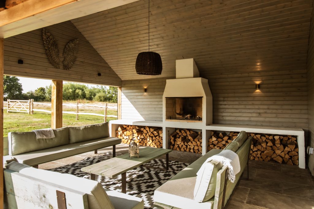 Whitfield House outdoor living room with fireplace and logs stacked up