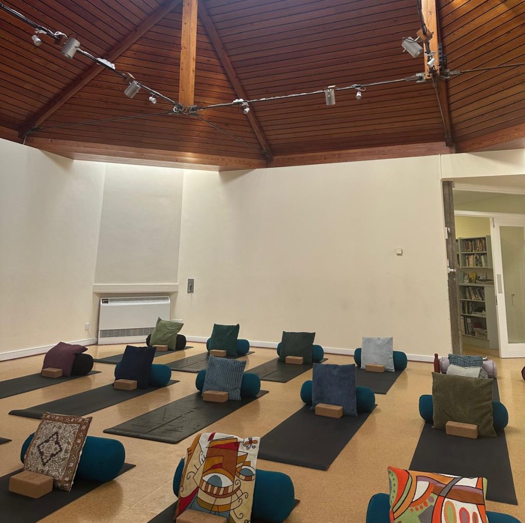 Blackheath Quaker Meeting hall set up for yoga with mats, bolsters and cushions. The wooden ceiling and glass lantern light is visible.